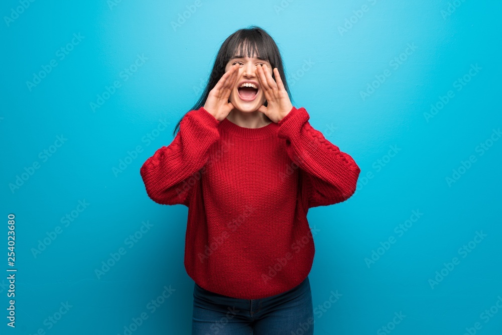 Woman with red sweater over blue wall shouting and announcing something Woman with red sweater over blue wall shouting and announcing something