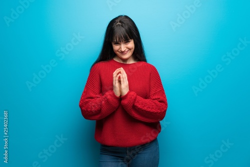 Woman with red sweater over blue wall scheming something