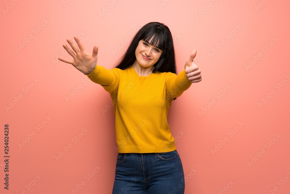 Woman with yellow sweater over pink wall counting six with fingers Woman with yellow sweater over pink wall counting six with fingers