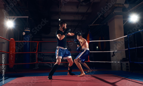 Two sporty boxers training kickboxing in the ring at the health club