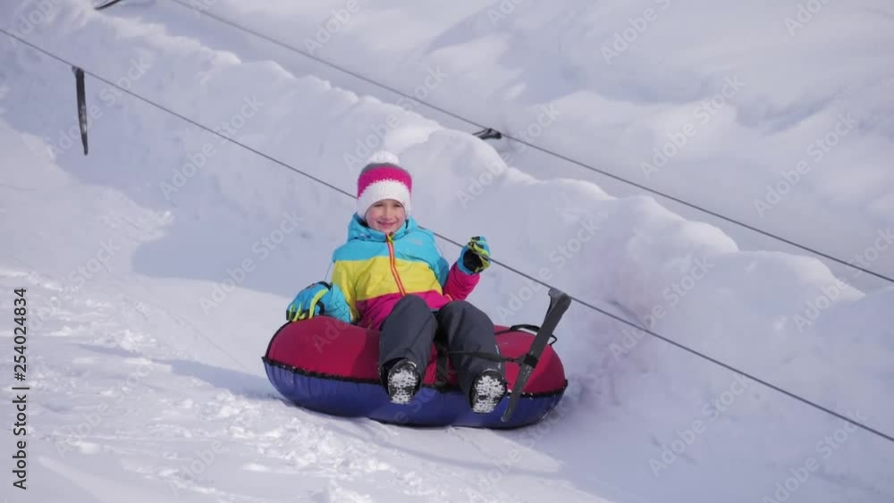 Young girl riding on inflatable snow tube from a hill. Young girl riding on inflatable snow tube from a hill.