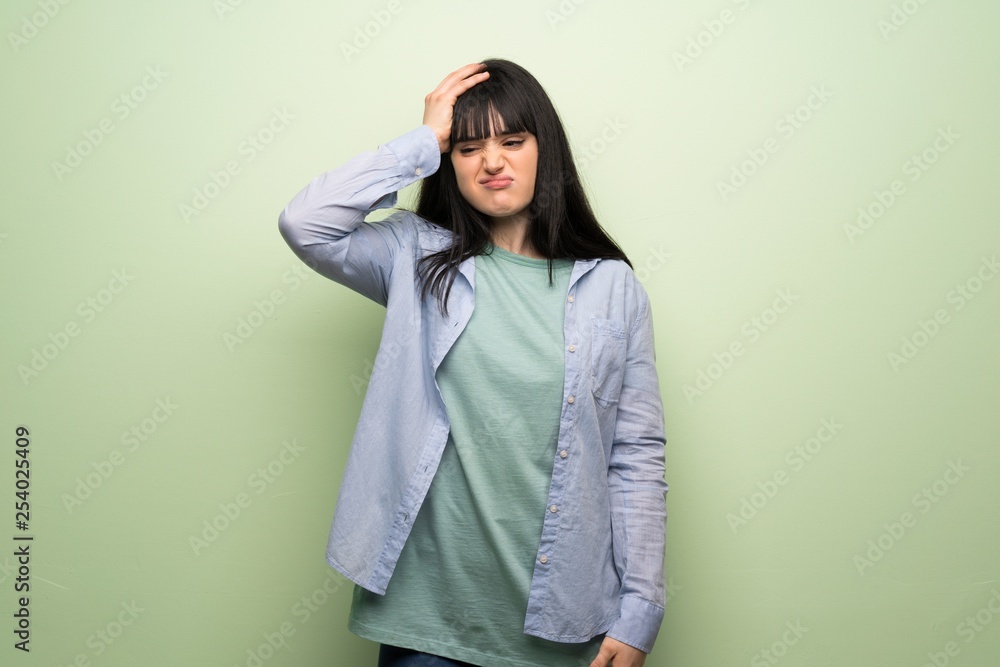 Young woman over green wall with surprise and shocked facial expression Young woman over green wall with surprise and shocked facial expression