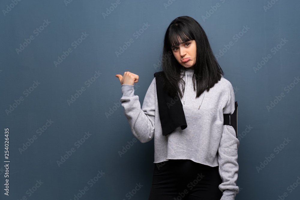 Young sport woman unhappy and pointing to the side