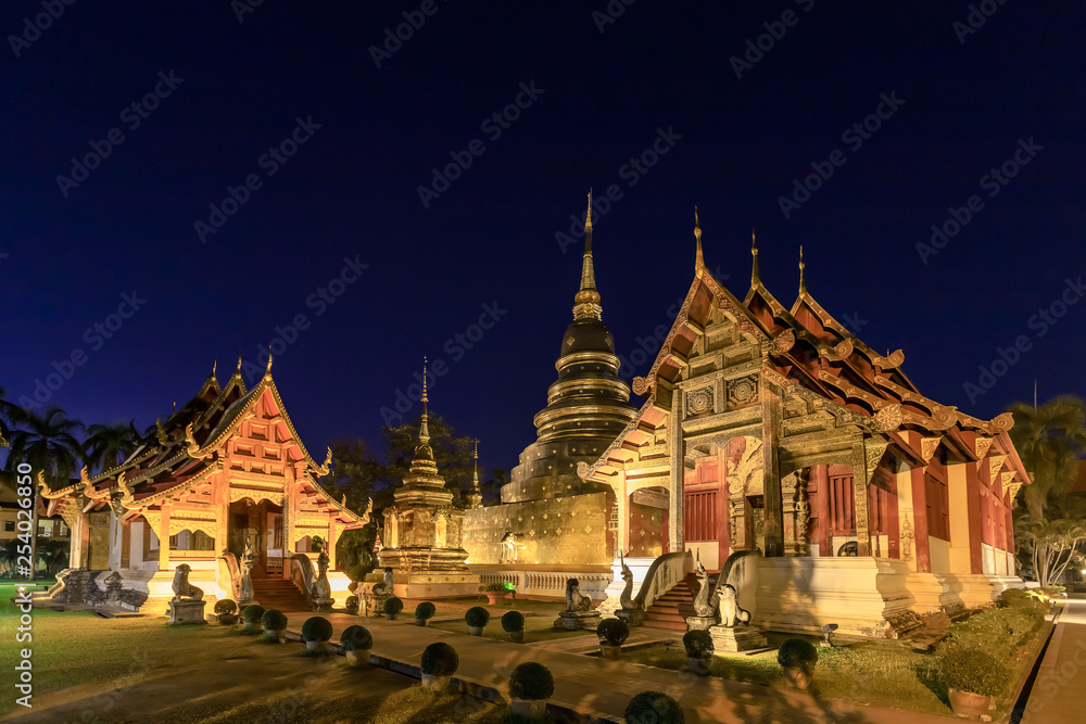 Naklejka premium Chapel and golden pagoda at Wat Phra Singh Woramahawihan in Chiang Mai at twilight or night with stars in sky