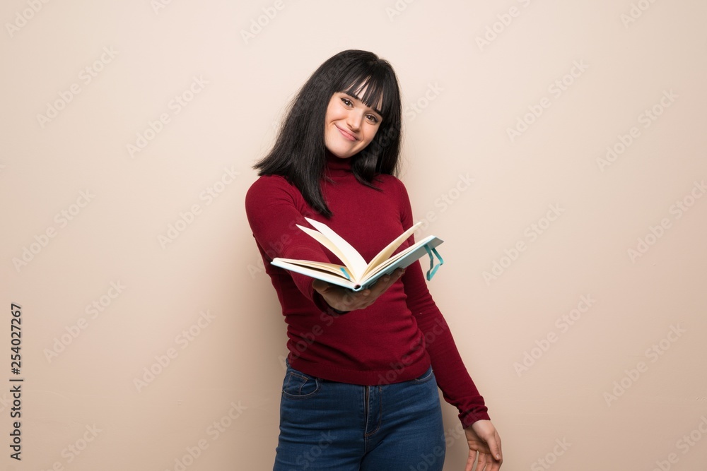 Young woman with red turtleneck holding a book and giving it to someone Young woman with red turtleneck holding a book and giving it to someone