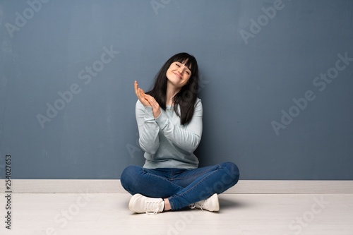Woman sitting on the floor applauding after presentation in a conference