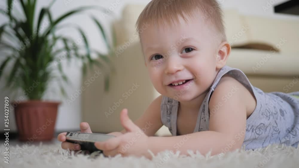 Little boy is watching cartoons on smartphone on the floor at home, lifestyle. Little boy is watching cartoons on smartphone on the floor at home, lifestyle.