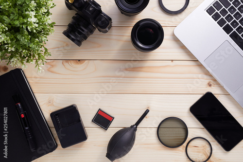 Top view of photographer desk with latptop, camera, lenses and accessories with copy space. Flat lay shot on wooden background. photo