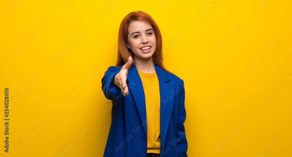 Young redhead woman with trench coat shaking hands for closing a good deal Young redhead woman with trench coat shaking hands for closing a good deal