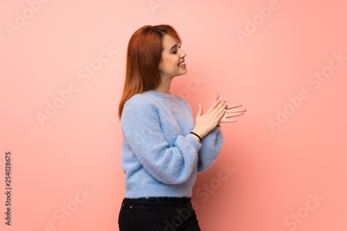 Young redhead woman over pink background applauding after presentation in a conference