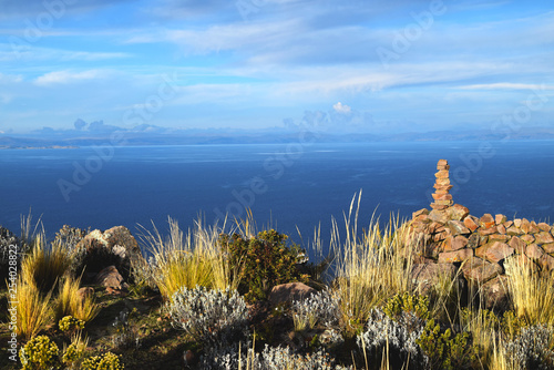 Yellow grass, stones and beautiful background of the blue water, clouds and sky. Photo taken in Peru photo