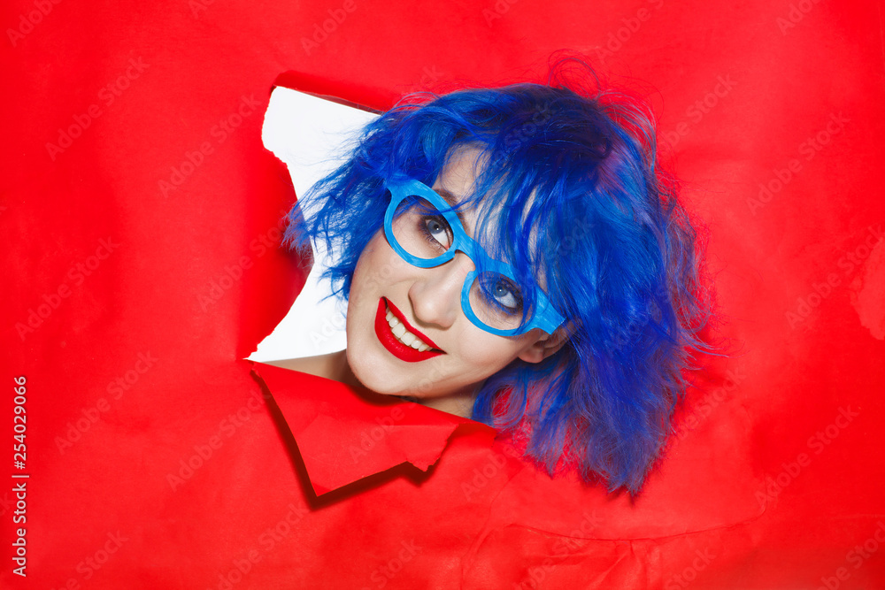 Φωτογραφία Portrait of an extravagant woman with blue hair and glasses looking through hole