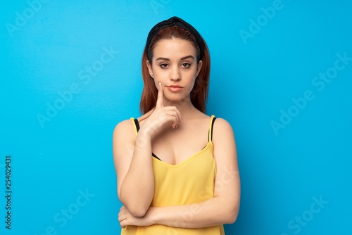 Young redhead woman over blue background Looking front