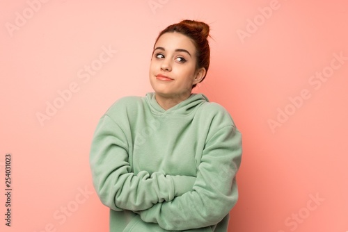 Young redhead woman with sweatshirt making doubts gesture while lifting the shoulders