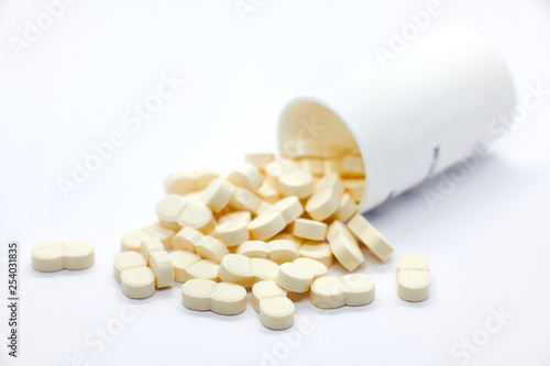 Fotografi pills coming out of bottle on white background