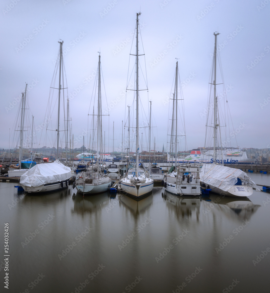Parked boats in still water during a foggy morning