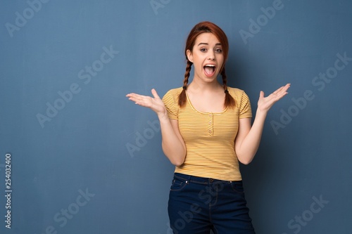 Young redhead woman over blue background with surprise and shocked facial expression