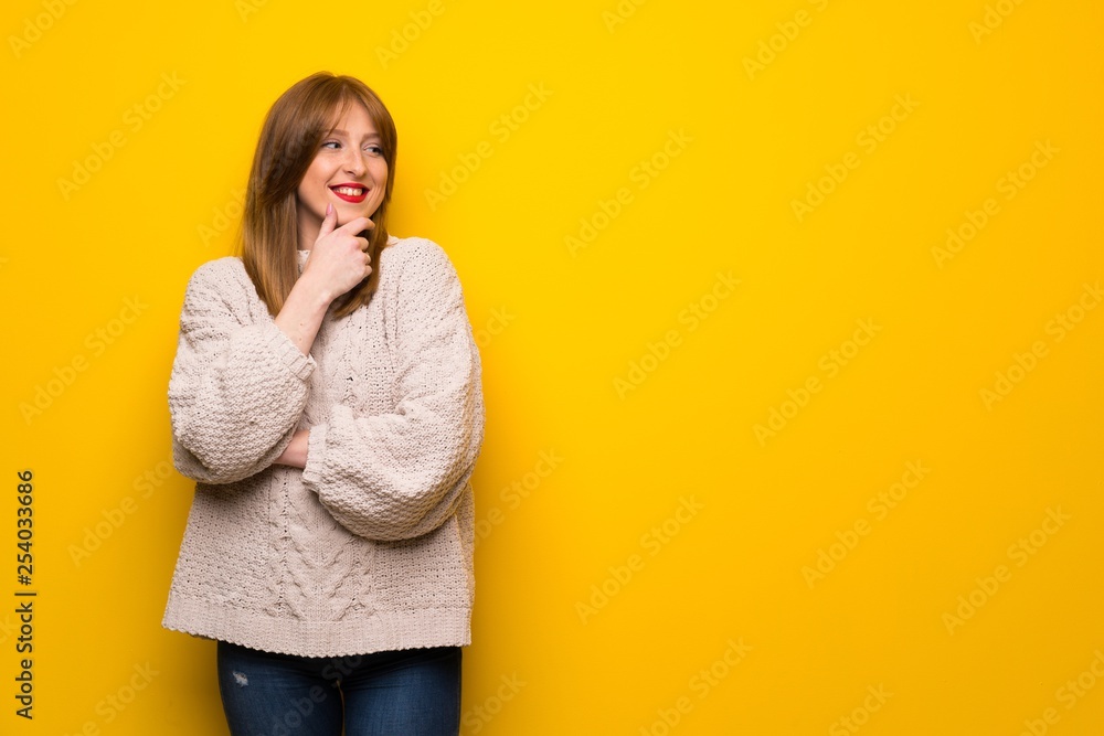 Redhead woman over yellow wall looking to the side Redhead woman over yellow wall looking to the side