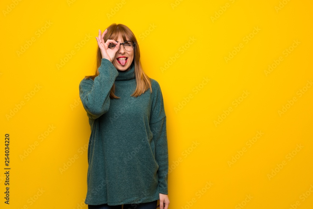 Woman with glasses over yellow wall makes funny and crazy face emotion Woman with glasses over yellow wall makes funny and crazy face emotion