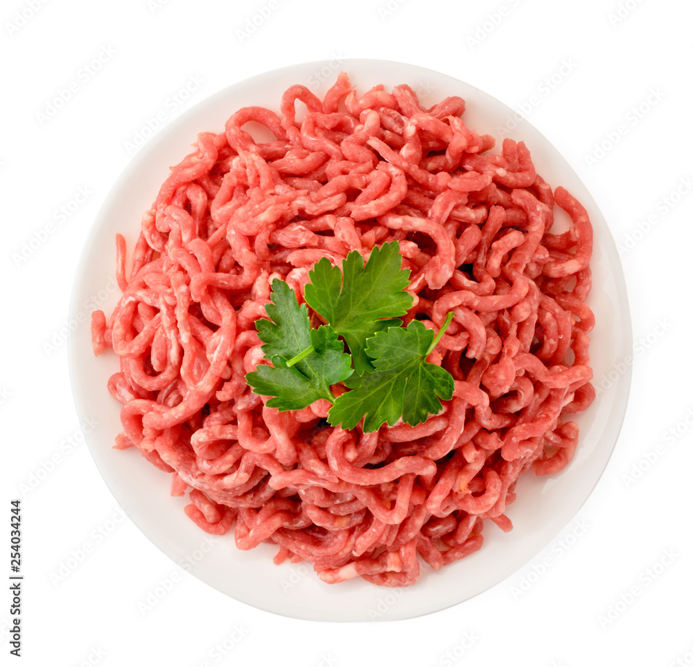 Minced meat in a plate and parsley leaves on a white. The form of the top. Minced meat in a plate and parsley leaves on a white. The form of the top.