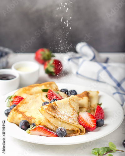 Thin pancakes with strawberries and blueberries, jam, condensed milk, delicious Breakfast. Russian traditional dessert for Shrovetide celebration (maslenitsa). French crepes photo