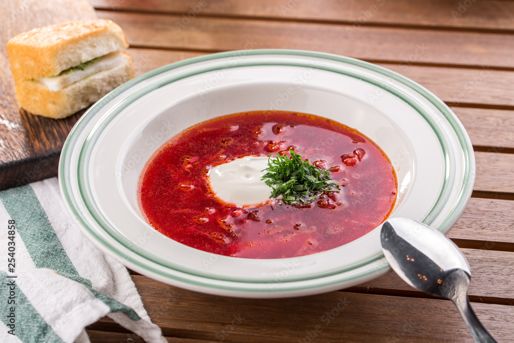 Red beetroot soup borshch with beef and sour cream on wooden table Red beetroot soup borshch with beef and sour cream on wooden table