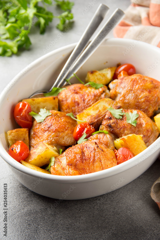 Baked chicken thighs (legs) with crispy crust, potatoes and cherry tomatoes. Simple delicious homemade dinner, traditional meal. Everyday food cooked in oven Baked chicken thighs (legs) with crispy crust, potatoes and cherry tomatoes. Simple delicious homemade dinner, traditional meal. Everyday food cooked in oven
