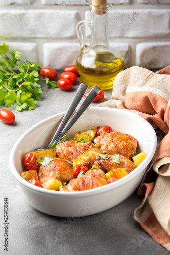 Baked chicken thighs (legs) with crispy crust, potatoes and cherry tomatoes. Simple delicious homemade dinner, traditional meal. Everyday food cooked in oven