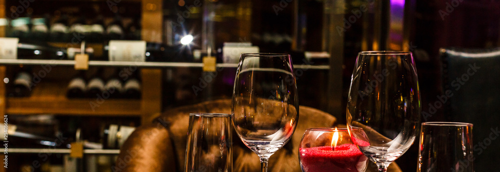 Two glasses of wine white and red standing on a table with candle in the sun light Two glasses of wine white and red standing on a table with candle in the sun light