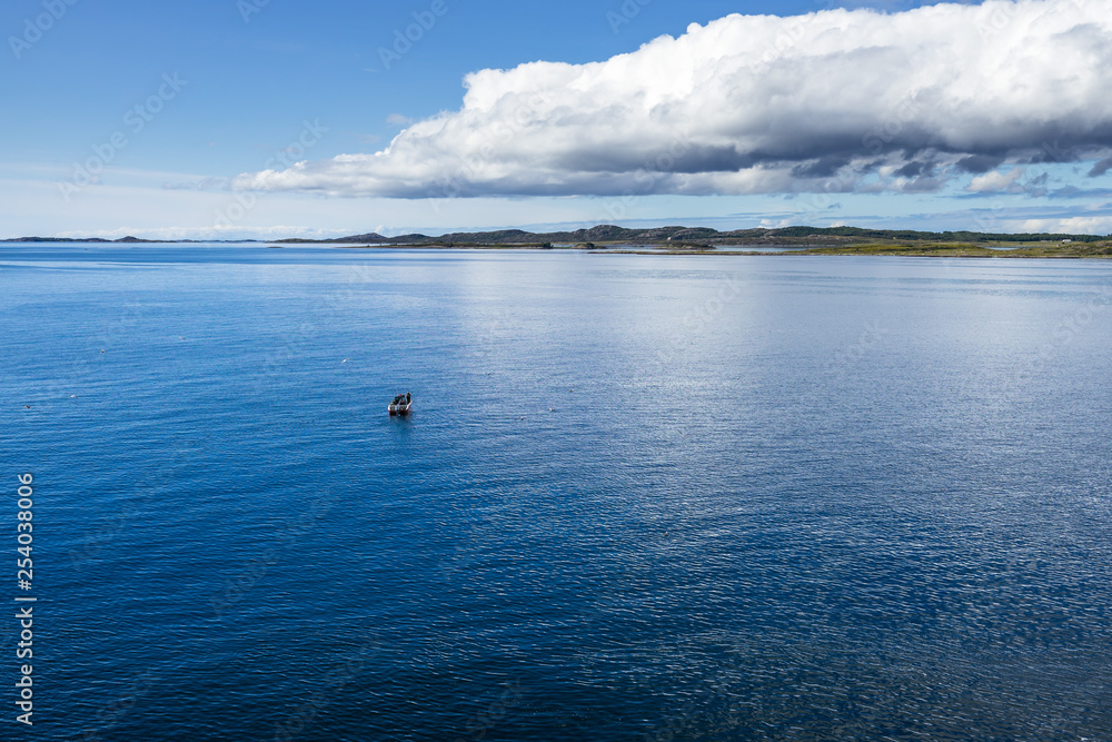 A small fishing boat near Western Norway coastline in a bright sunny day during summer season