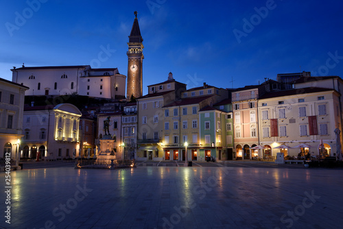 Lights reflected on Tartini Square Plaza in Piran Slovenia with Tartini statue monument, St. George's Parish Church with belfry tower at dusk twilight photo