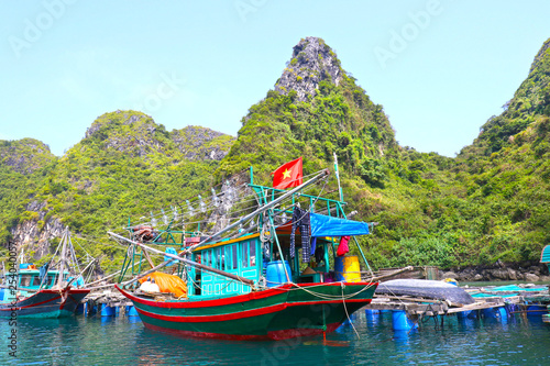 Halong Bay  Vietnam. Small Wooden Fishing boats docked at Floating Fishing village with Vietnam National Flag