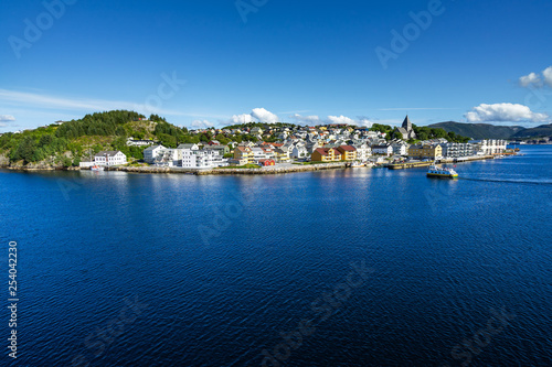 Sunny cityscape of Kristiansund with a ferry boat approaching Nordlandet island, More og Romsdal, Norway