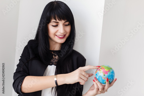 Young Beautiful smiling brunette woman dressed in a black business suit holding a globe of the planet Earth.