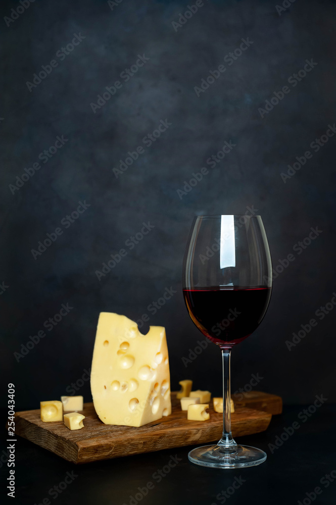 wine and delicious cheese on a cutting board, background stone