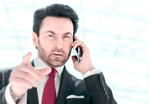 businessman talking on the phone and pointing at you