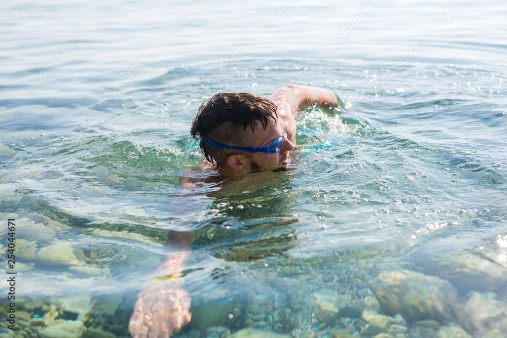 The concept of an active lifestyle: a man swims in swimming goggles