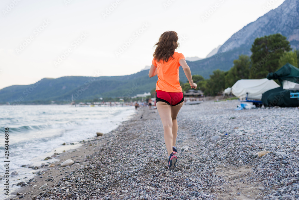 Active lifestyle: a slim woman runs along the beach.