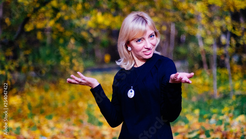 bright beautiful happy blonde woman with blue eyes in a black dress says something and actively uses gestures in her explanations.