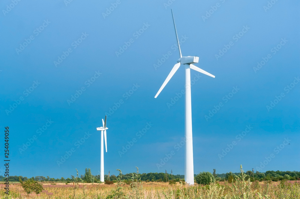 White wind power plants. Two wind turbines in the field. White wind power plants. Two wind turbines in the field.