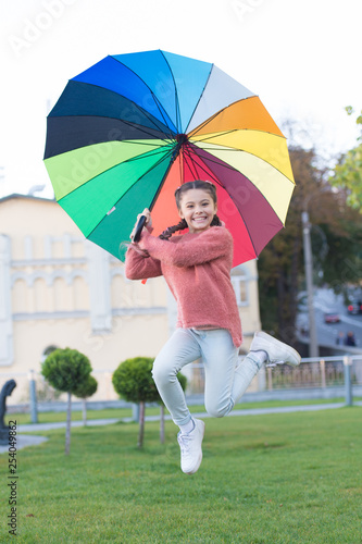 Happy and free. cheerful child. Spring style. Rainbow after rain. Little girl under colorful umbrella. Positive mood in autumn weather. Multicolored umbrella for little happy girl. Feeling happy
