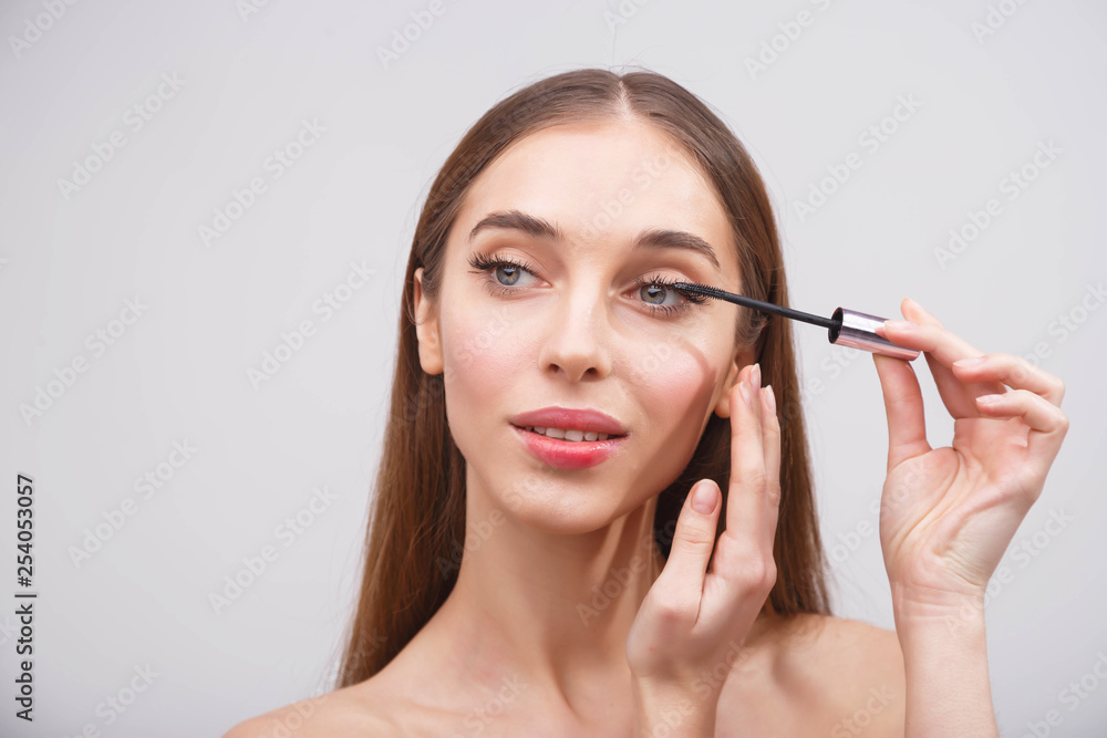 Young beautiful woman applying mascara makeup on eyes by brush Young beautiful woman applying mascara makeup on eyes by brush