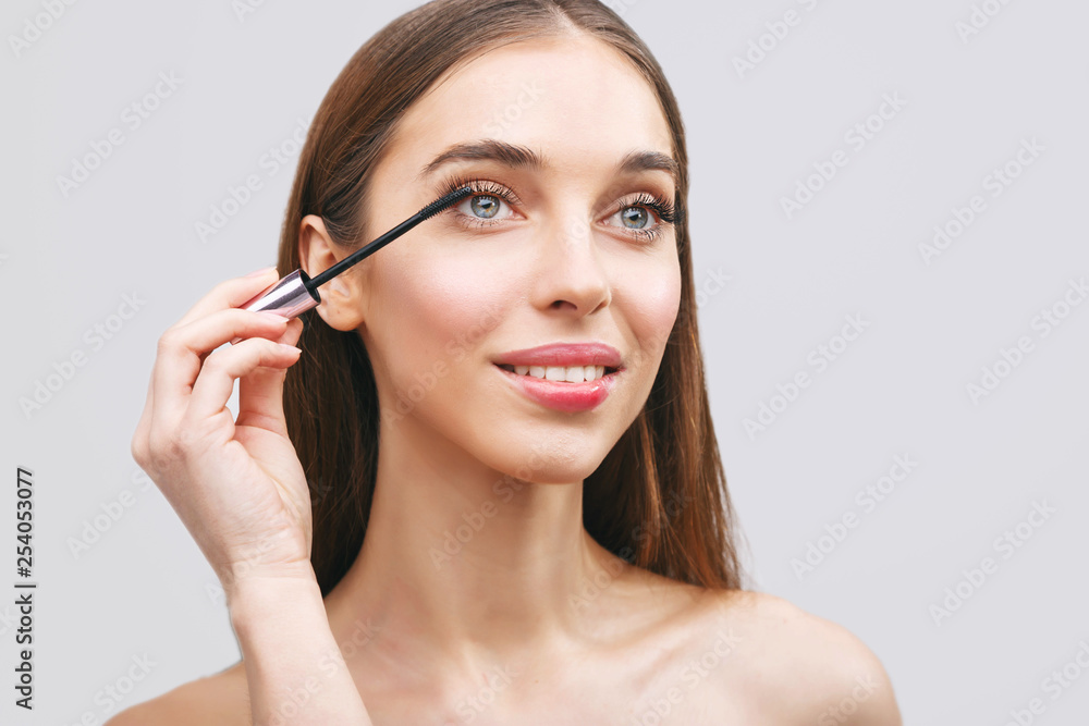 Young beautiful woman applying black mascara makeup on lashes by brush Young beautiful woman applying black mascara makeup on lashes by brush
