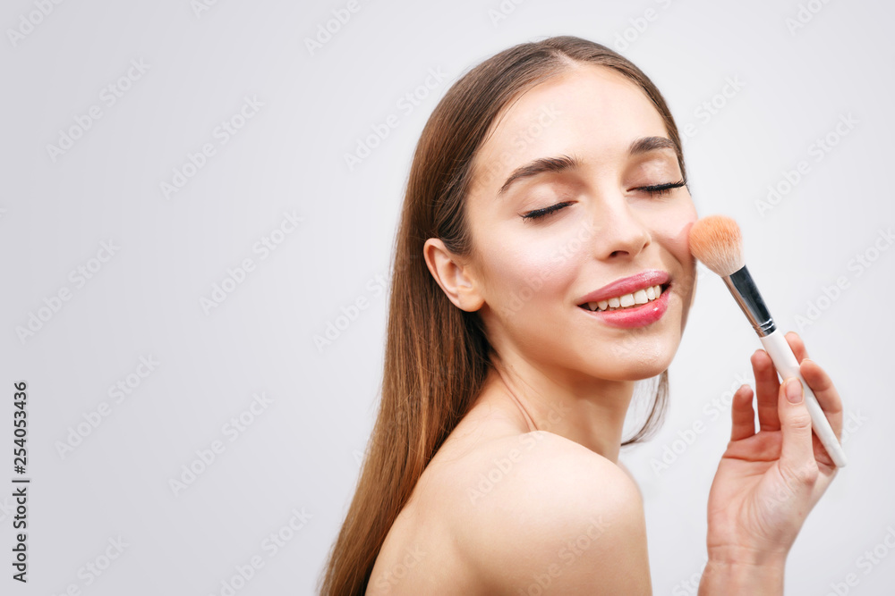 Gentle woman holding makeup brush over white Gentle woman holding makeup brush over white