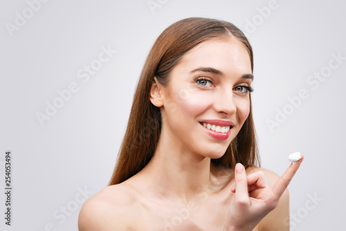 Beautiful young woman applying a creme on her face isolated on white background