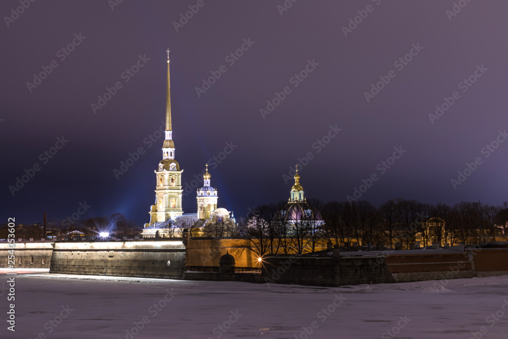 Obraz premium Peter and Paul Fortress of St. Petersburg, Russia in the evening or in the night and Neva river covered with the ice and snow in the cloudy weather