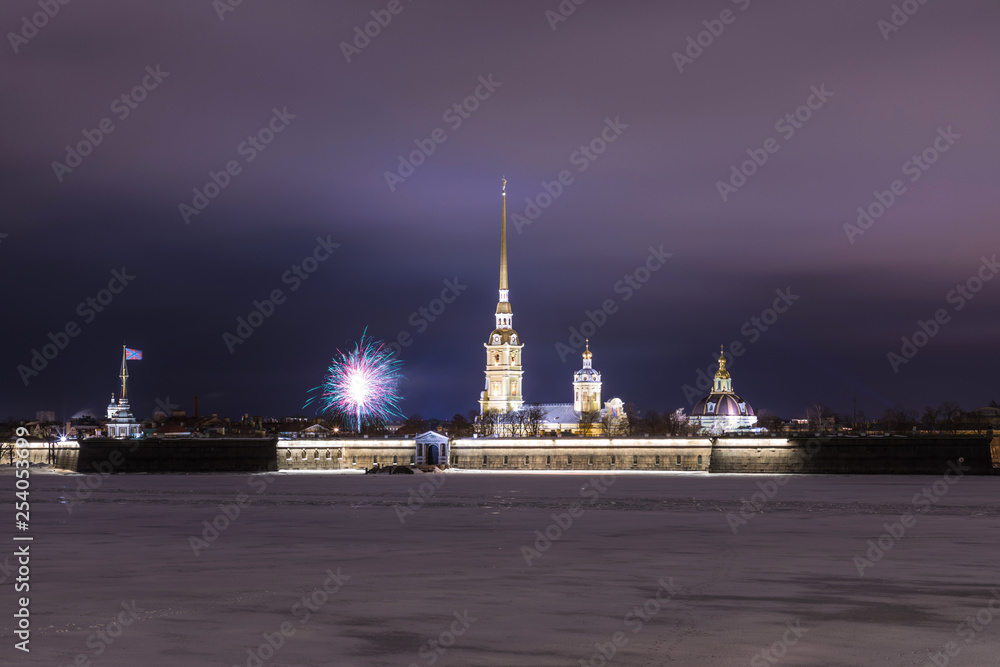 Peter and Paul Fortress of St. Petersburg, Russia in the evening or in the night and Neva river covered with the ice and snow in the cloudy weather an with the fireworks in the sky