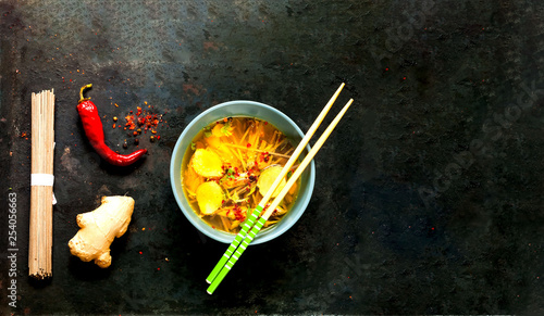 Light Soup in Asian Style with Buckwheat Noodles Soba and Salmon on black old metal background.