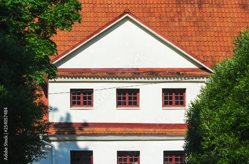 House with White Gable and Red Ceramic Roof Tiles Surrounded by Green Trees