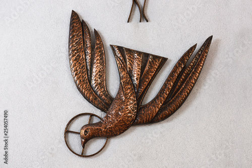 Photography Bronze sculpture of a dove representing the Holy Spirit of God on a stucco wall